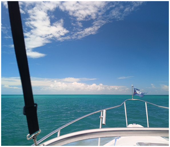 View from a boat looking out at the sea under a partly cloudy sky.